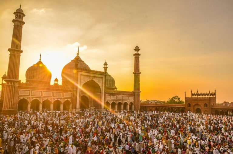 Vibrant scene of a large crowd gathered for Ramadan prayers at Jama Masjid during a stunning sunset.